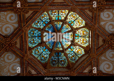 Looking up from the interior of the Modernista Sant Pau at the stained glass ceiling dome Stock Photo