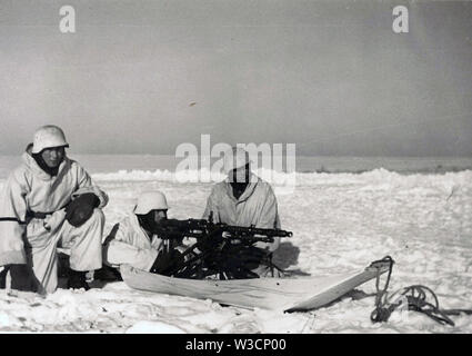 German Soldiers in White Winter Camouflage with a Heavy Machine Gun MG34 mounted on a Sled in thick Snow on the Russian Front 1942 Stock Photo