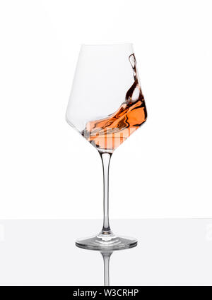 Glass of amber wine with splashes on white table. Stock Photo