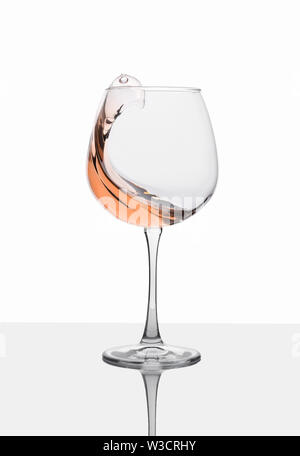 Glass of amber wine with splashes on white table. Stock Photo