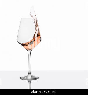 Glass of amber wine with splashes on white background. Stock Photo