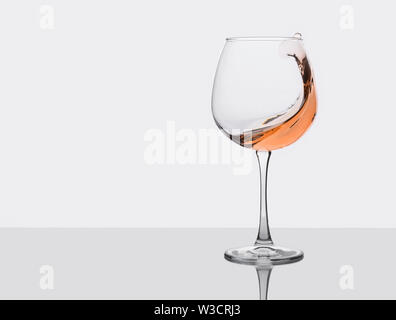 Glass of amber wine with splashes on gray background. Stock Photo