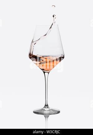 Glass of amber wine with splashes isolated on white. Stock Photo