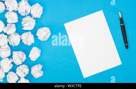 blank white paper and pencil beside crumpled paper balls Stock Photo