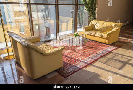Hall building with two leather couches and glass table in bright sunlight Stock Photo