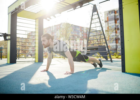 Concentrated powerful young athlete in sportswear pushing yourself away from ground while training alone Stock Photo