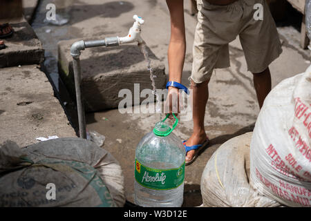 A young boy filling a plastic water container from a standing water pipe within a poor community,Cebu City,Philippines. Stock Photo