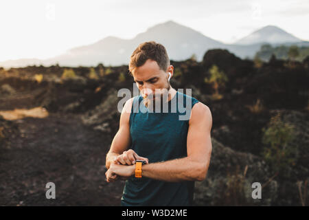 Runner checking training results on smart watch. Male athlete using fitness tracker. Stock Photo