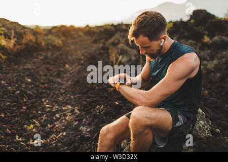 Runner checking training results on smart watch. Male athlete using fitness tracker. Stock Photo