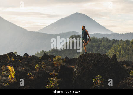 Man doing stretching and preparing for workout and running outdoors. Amazing mountain view on background. Adventure sports concept. Stock Photo