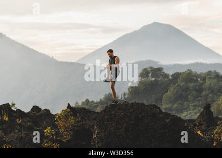 Man doing stretching and preparing for workout and running outdoors. Amazing mountain view on background. Adventure sports concept. Stock Photo
