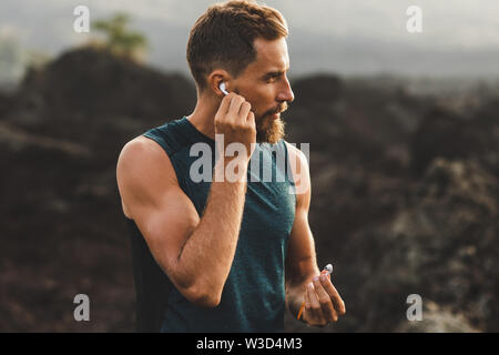 Man using wireless earphones air pods on running outdoors. Active lifestyle concept. Stock Photo