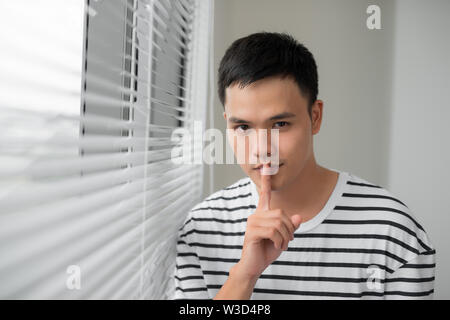 Attractive man with finger on lips making silence gesture. Shh!!! Stock Photo