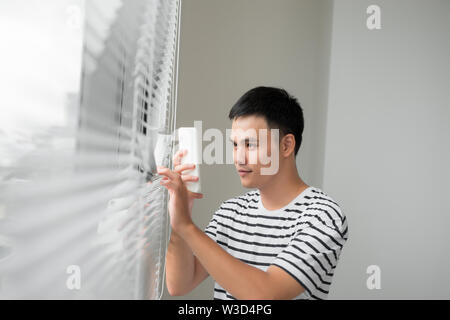 Handsome young man taking photo through the window with mobile Stock Photo