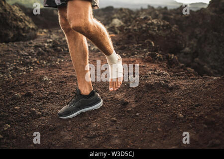 Man's ankle in compression bandage. Leg injury while trail running outdoors.  First aid for sprained ligament or tendon. Stock Photo