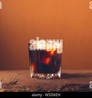 A glass of strong alcoholic drink whiskey brandy on a dark wooden background. Selective focus. Square frame Stock Photo