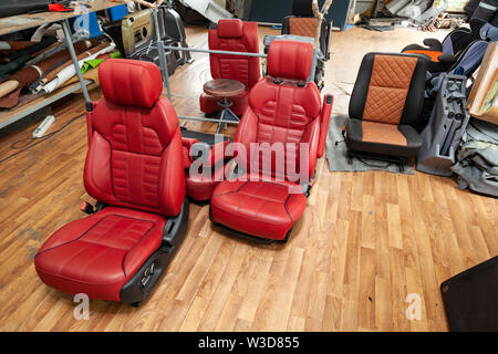 Four sport seats with red leather trim, located on the floor in the workshop for repair and tuning of cars and vehicles Stock Photo