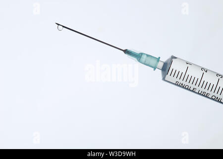 The end of the syringe with a needle filled with liquid on a light background. Stock Photo