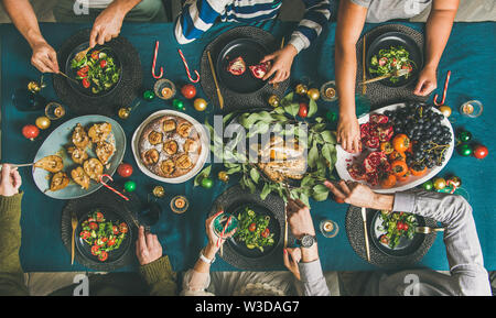 Human hands holding glasses with drinks and eating at Christmas Stock Photo