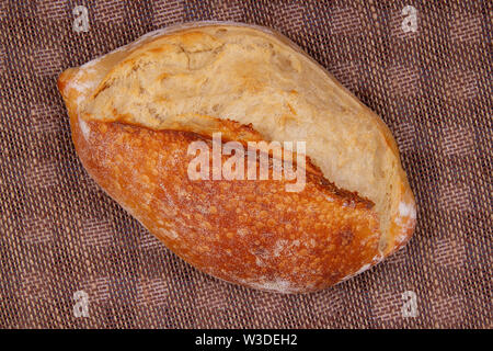 Top view of whole loaf sourdough bread lying on table covered with sacking Stock Photo