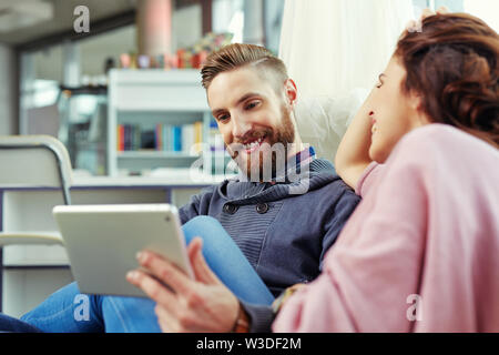 Young hipster with his girlfriend browsing internet on digital tablet Stock Photo