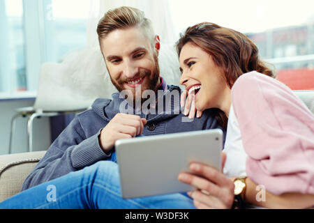 Happy couple using tablet and laughing Stock Photo