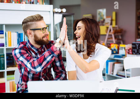 Two happy coworkers, designers making high  five in modern office Stock Photo