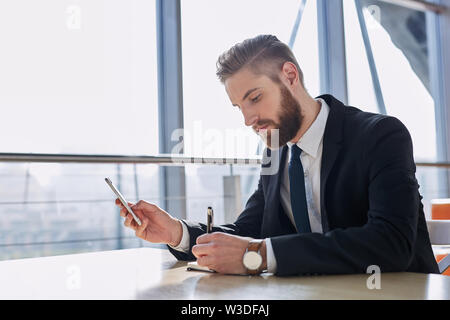 businessman writing notes from smartphone at modern office Stock Photo