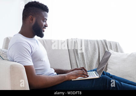 Millennial black man working on laptop in home office Stock Photo