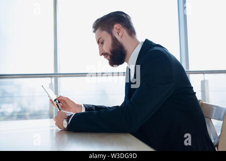 Stylish hipster businessman with smartphone at modern office Stock Photo