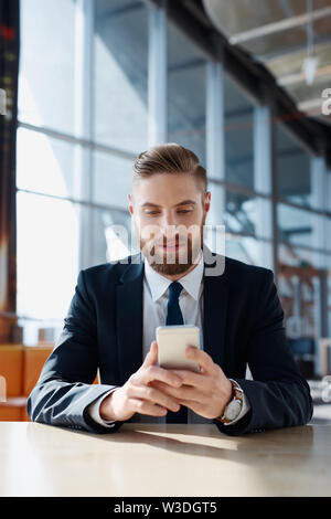 Handsome businessman browsing internet on smartphone at office Stock Photo