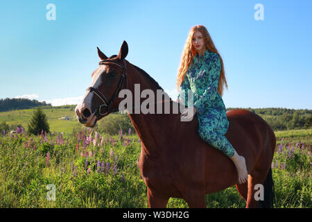 Portrait of young pretty cheerful woman with horse at summer green park Stock Photo