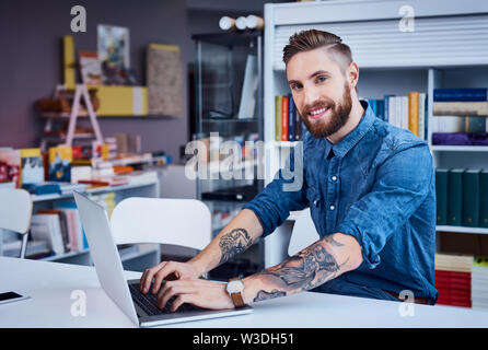 Happy designer, hipster working on laptop in office Stock Photo