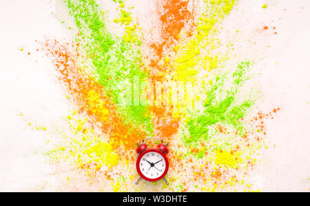 Coloured holi powder explosion out of alarm clock on white Stock Photo