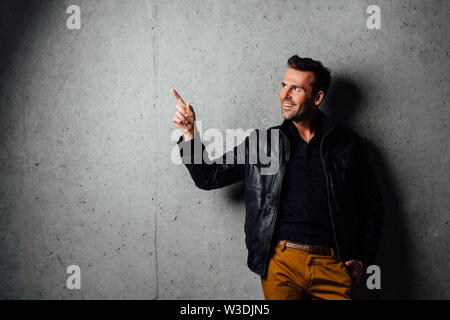 Handsome man pointing at the concrete wall Stock Photo