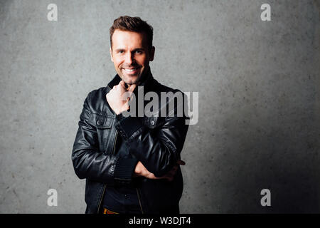 Young handsome man smiling  isolated against concrete wall Stock Photo
