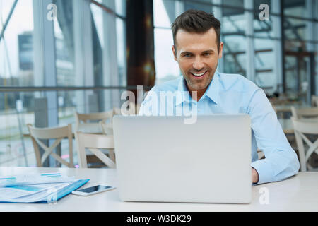 Handsome confident businessman working at modern office on laptop Stock Photo
