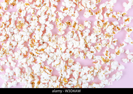 Popcorn scattered at the pastel pink background and a space for copyspace. Popcorn on a red background. Flat lay. Copyspace. Cinema Concept. Stock Photo