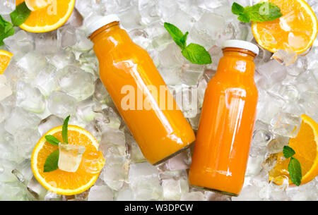 Carrot smoothie in glass bottle with fresh oranges on ice Stock Photo
