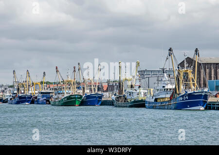 IJmuiden, the Netherlands, July 14, 2019: green and blue fishing trawlers are moored in Vissershaven harbour on a cloudy day in summer Stock Photo