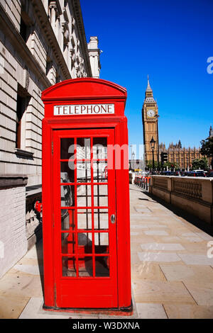 Iconic Red Telephone Booth and Big Ben Clock Tower over blue sky. Nobody present. Stock Photo