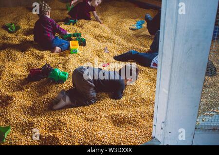 Kids playing with toys in corn filled box Stock Photo