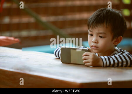 Kid boy playing and looking smartphone Stock Photo