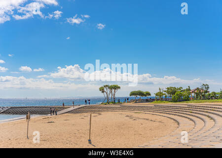 Beach umbrellas and palm trees on the Sunset beach in Chatan City in the American Village of Okinawa island in Japan.