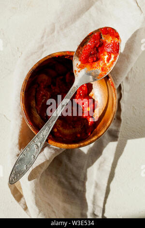 Traditional Italian tomato sauce marinara for pasta or pizza in the spoon and bowl on white background top view.Food leftovers after lunch Stock Photo