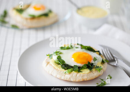 Healthy homemade breakfast or brunch (quick meal)-fried eggs with Indian spices and sautéed spinach used to top toasted pitas with turmeric yogurt Stock Photo