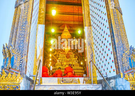BANGKOK, THAILAND - APRIL 22, 2019: The view through the open doors on the monks praying in Ordination Hall of Phra Ubosot shrine in Wat Pho complex, Stock Photo