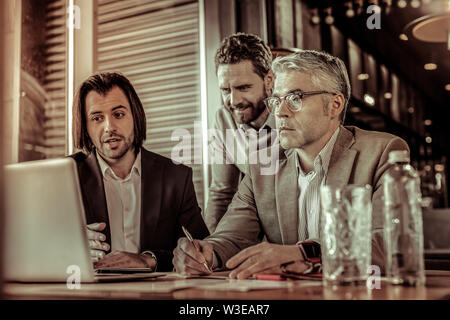 Attentive aged businessman making notes during conference Stock Photo
