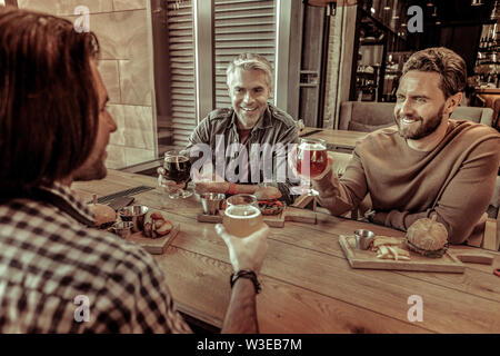 Positive delighted bearded male person leaning on table Stock Photo