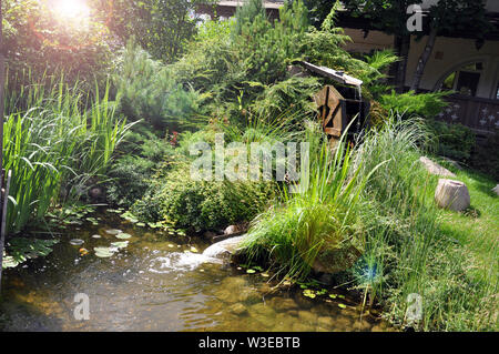 Landscape and arrangement. Driving mill wheel with falling water in the garden. Stock Photo